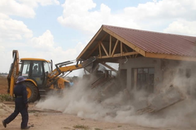 A bulldozer destroys a house that was illegally built on State land along High Glen Road in Harare yesterday