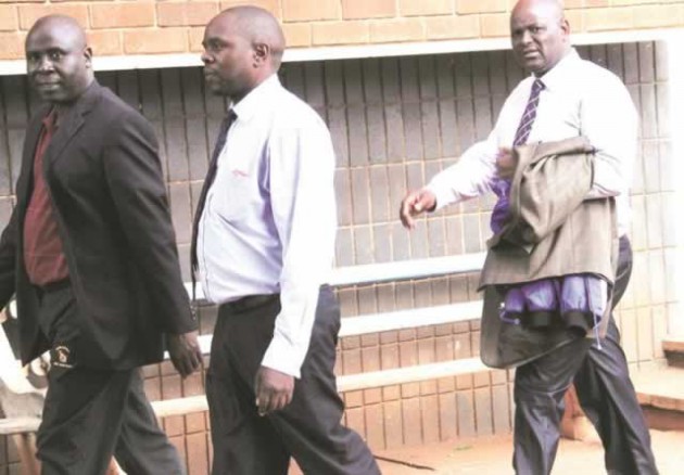 CMED boss Davison Mhaka (left) walks out of the Harare Magistrates’ Court after paying his $500 bail. He is accompanied by two friends who unsuccessfully tried to conceal his blue jacket to avoid photographers. - Picture by John Manzongo