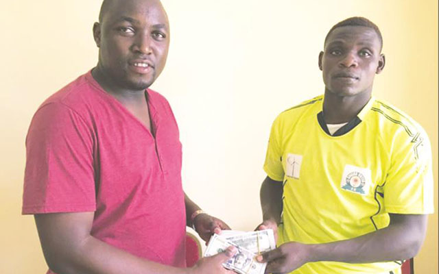ALL ABOUT THE BENJAMINS . . . Zimbabwe international defender Elisha  Muroiwa (right) is shown being handed the bills of cash by his agent in Tanza