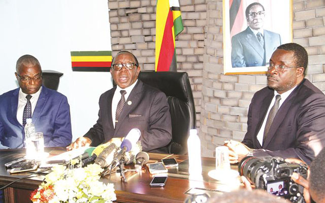 Information, Media and Broadcasting Services Minister Simon Khaya Moyo i reads a press statement on the expulsion of Vice President Emmerson Mnangagwa from Government in Harare yesterday. He is flanked by his permanent secretary, Mr George Charamba (right), and Director Media Services Retired Major Anywhere Mutambudzi.- Picture by John Manzongo