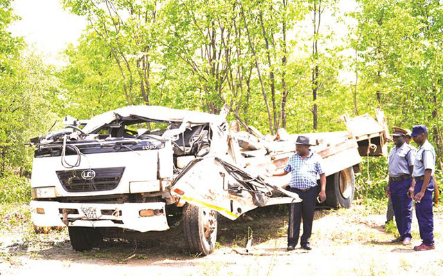 Tsholotsho South Member of Parliament Zenzo Sibanda and police officers view the wreckage of a Nissan UD truck that overturned and killed 21 people near Jimila Shopping Centre, Lucu Village, in Tsholotsho on Saturday. — (Picture by Obey Sibanda)